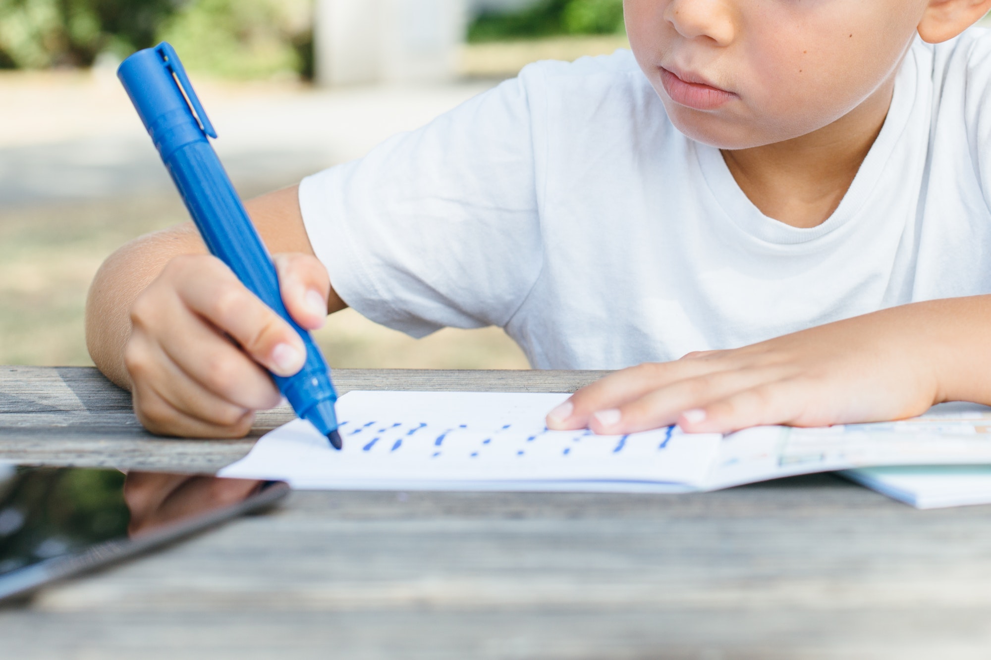 Close-up of kid writing in notepad
