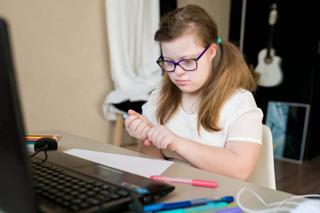 teenager girl with Down syndrome learning online at home. Distance learning by video call on laptop