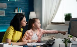 Small student studying with parent on internet